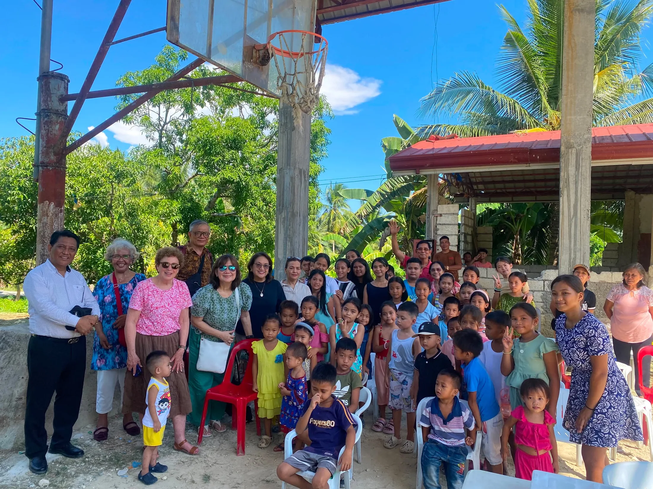 Children and adults gathered beneath a basketball hoop outdoors in Cebu