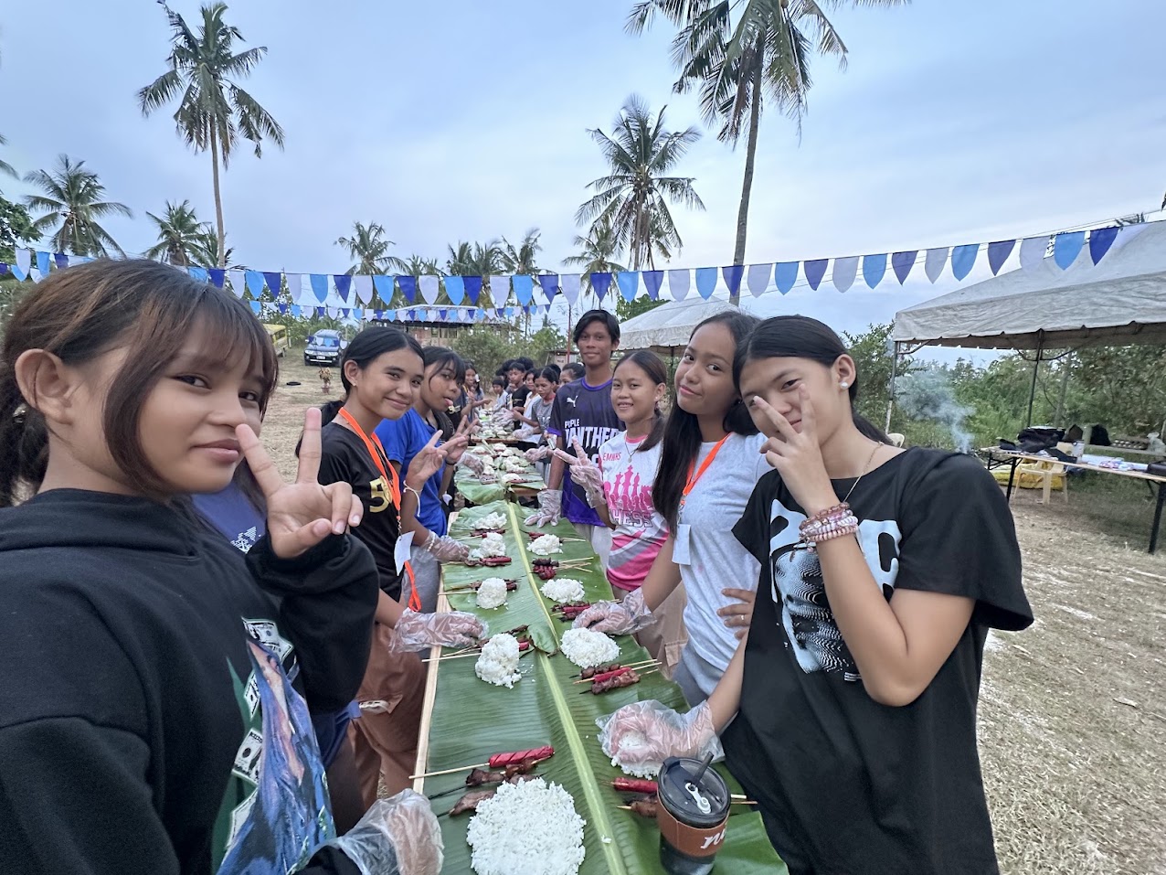 Young people gathered around a shared meal outdoors at Mt. Moriah